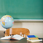 globe and books on teacher's desk infront of chalkboard